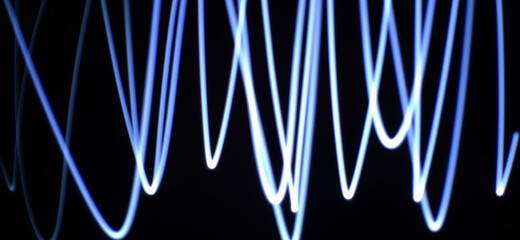 Abstract concept of Neon Blue wave pattern abstract Streaming through the isolated black background with copy space made using Light photography technique called Light painting. Light trails.