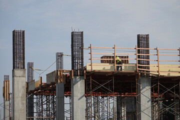 A new construction site is shown during the day, featuring rebar, concrete, wood, scaffolding, and wood.