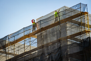 Two workers at a construction site are painting the walls of a new apartment. 