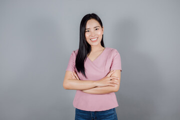 Beautiful asian woman with long dark hair crossed arms on gray background