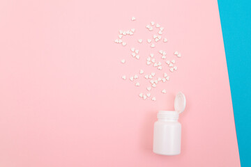 Global Pharmaceutical Industry and Medicinal Products - White Pills or Tablets Scattered from the Pill Container, Lying on Split Blue and Pink Background