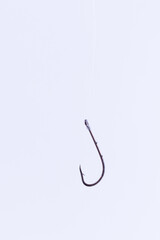 Black Fishing Hook Hanging on a Fishing Line Against a White Background