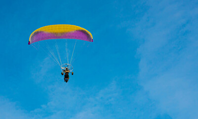 paraglider with a motor flies in the blue sky