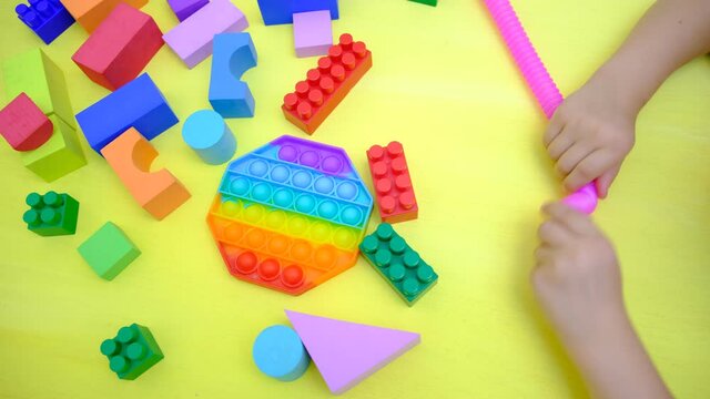 Child playing with antistress sensory toy fidget push pop tube and other toys. Silicone toy 