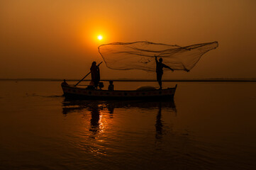 beautiful silhouette pictures  with boat and fisherman with net during sunset in golden light 