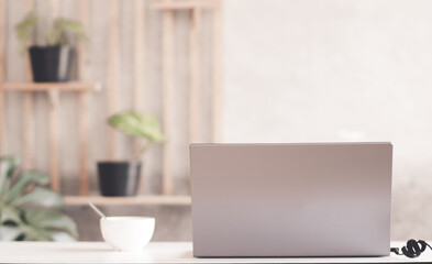 Close up view of comfortable office desk with laptop, mug, copy space on white table in glass partition office