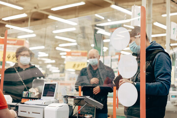 Man in protective medical mask buying food at grocery store or supermarket during quarantine, lockdown, coronavirus pandemic.