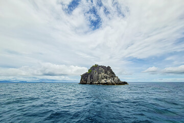 Island rock pinnacle in wide open ocean sea with cloud blue sky background landscape in Thailand