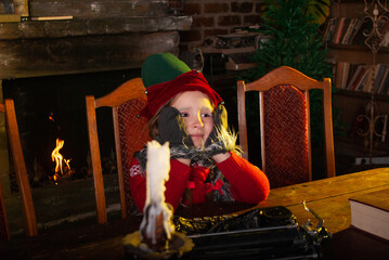 a little girl sits at a large table in the santa claus house for the New Year 2021 and Christmas in a cat