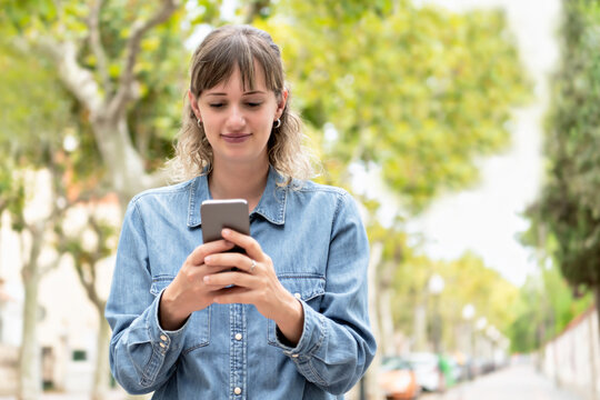 A woman using her phone with both hands outside