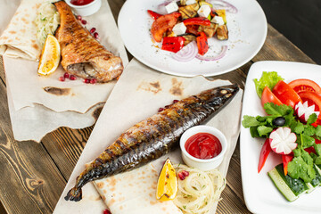 grilled mackerel and a salad of fresh vegetables. Serving on a wooden Board on a rustic table. Barbecue restaurant menu, a series of photos of different meats anf fish