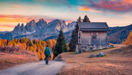 Photographer walks on the road on Fuchiade valley. Splendid evening view of Dolomite Alps, Italy,...