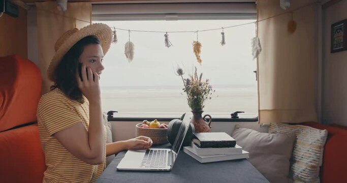 Young woman wearing hat in campervan phoning with beatiful ocean view shot in 4k