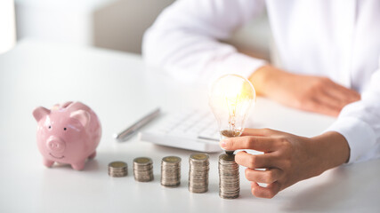 business woman holding a coin in a piggy bank On a table with sunlight. Money Saving Ideas for Financial Accounting