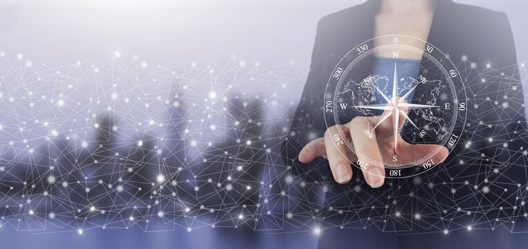 Navigation concept. Map and innovation concept. Hand touch digital screen hologram compass sign on city light blurred background. The compass navigate for business