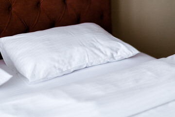 Close-up of clean white soft pillow on the comfortable bed in the bedroom.