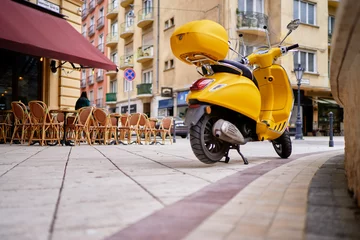 Schilderijen op glas Motor buiten. Gele retro-stijl scooter op de straat van de stad. © luengo_ua