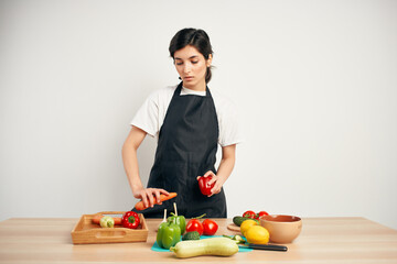 housewife in a black apron in the kitchen cutting vegetables healthy eating