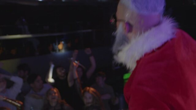 Santa Claus having fun with cheerful energetic crowd, waving hands and dancing.