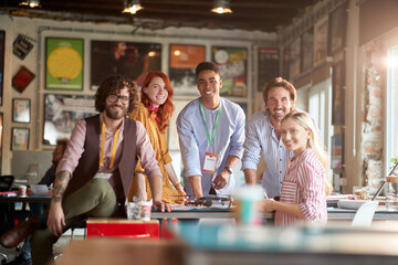 Group of young creative people in the office is posing for a photo while working together