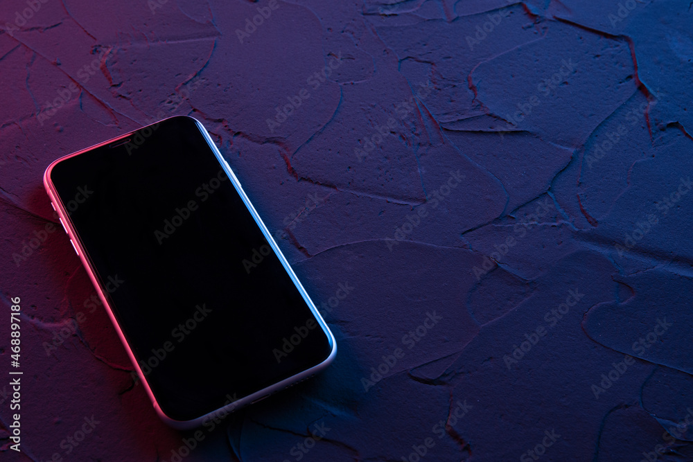 Wall mural mobile smartphone on dark red blue neon colors. mock up.perspective view. the layout of the device. 