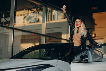 Fototapeta na wymiar Woman in black hat standing by her new white car