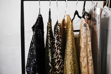 bright shiny cocktail dresses on a hanger in the dressing room. outfits for the new year party 2021. trendy dresses from the new christmas collection