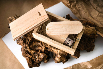     wooden usb flash drive in a box lies on a wooden table close-up. modern data storage technologies. flash drive template for applying a logo. top view mockup                           
