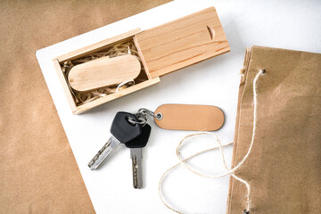   a wooden flash drive in a box lies on a wooden table. keys with a wooden natural keychain close-up. mockup top view                             