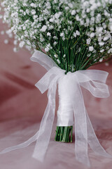 Fototapeta premium White bow on a bouquet of white flowers on a pink background