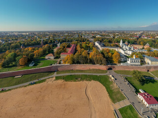 Fototapeta na wymiar Panoramic aerial view of the Kremlin in Veliky Novgorod, golden autumn in the city, yellow treetops, a bridge over the Volkhov river, city sandy beach, a fortress.