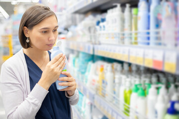 Young woman customer choosing sunscreen lotion at the pharmacy store