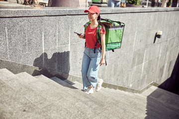 Woman worker of food delivery service walking down street