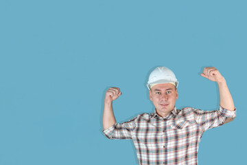 Handsome strong man builder in a white helmet on a blue background, Copyspace