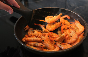 the cook fries shrimps in garlic sauce in a frying pan close-up. asian shrimp in sauce close-up