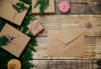 Boxes packed in kraft paper,branches on a wooden background. An envelope,letter of congratulations. Christmas,New Year.