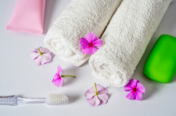 Obraz na płótnie Canvas Toothbrush, toothpaste and white towels, pink flowers with soap. Aromatherapy and Oral care, body hygiene and morning daily routines.
