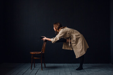 young beautiful girl in the studio on a black background, she is wearing a trench coat and black lingerie