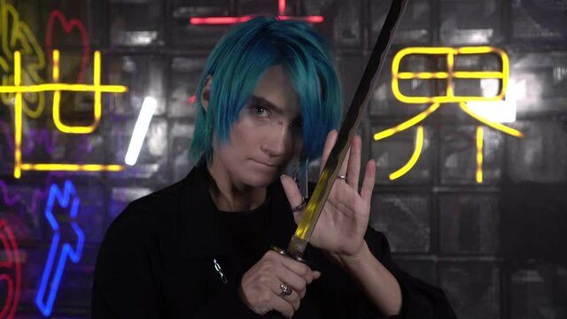 A young man with blue hair holds a katana sword. Japanese anime cosplay. inscription on the background in Japanese: path from darkness to light