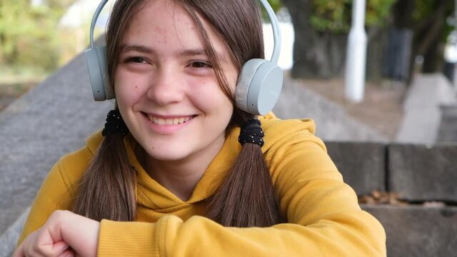 A 13-year-old teenage girl listens to music and laughs.