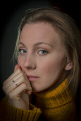 portrait of a young woman in a yellow sweater on a black background