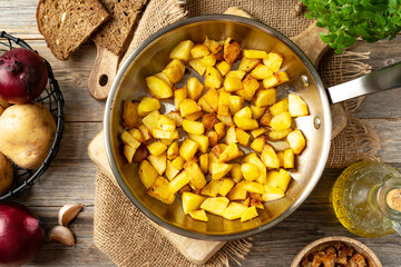 Fried potatoes in a frying pan on a gray wooden table top view