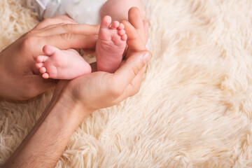 Mom holds in his hands a small baby foots. Small legs of a newborn baby in the hands of mother. Baby foot massage