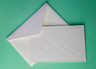 white paper envelope with blank invitation and on green background