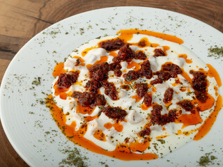 Ravioli with tomato paste and yogurt in a white plate on wood