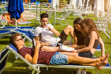 Friends relaxing on sun loungers in beautiful sunny day. - Powered by Adobe