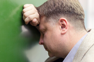 Obraz premium A tired adult teacher in the classroom leaned his head on the blackboard.