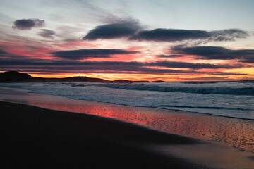 Fototapeta na wymiar Atardecer en la playa con el reflejo del sol en la arena de Nueva Zelanda