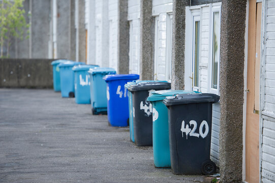 Household refuse wheelie bins on the street outside properties, Scotland, UK.