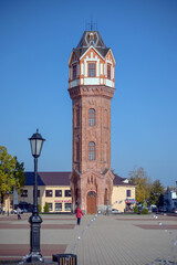 Obraz premium TA brick restored water tower in the Art Nouveau architectural style rises on the central square of the ancient city of Staraya Russa, Novgorod region. Industrial architecture of the early XX century